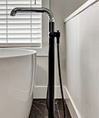 Floor mounted tub filler in black and chrome finish